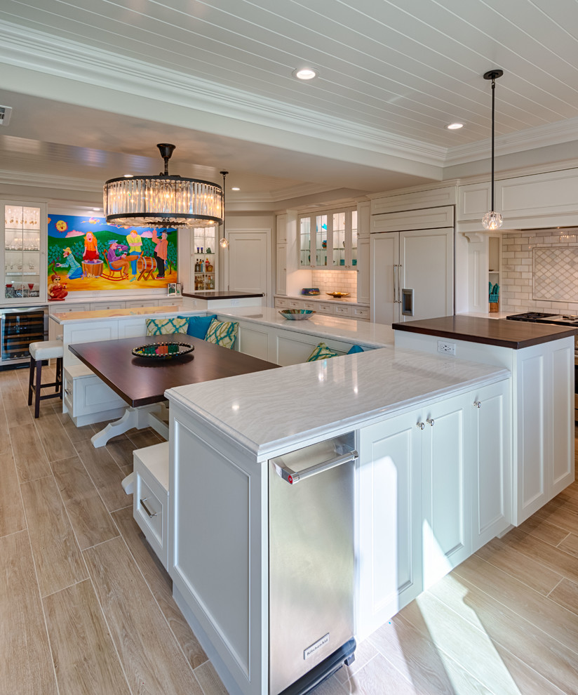 Photo of a large transitional u-shaped eat-in kitchen in Los Angeles with an undermount sink, recessed-panel cabinets, white cabinets, quartzite benchtops, grey splashback, marble splashback, panelled appliances, light hardwood floors, with island, beige floor and white benchtop.