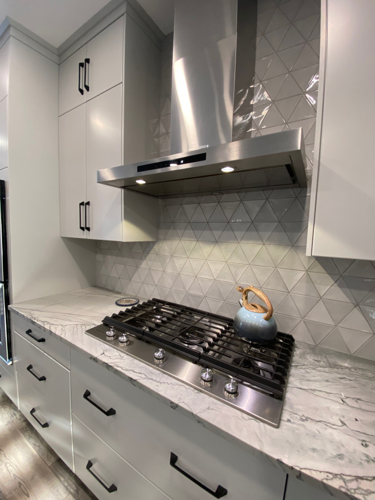 Mid-sized contemporary single-wall eat-in kitchen in Calgary with an undermount sink, flat-panel cabinets, grey cabinets, granite benchtops, grey splashback, ceramic splashback, stainless steel appliances, vinyl floors, with island, grey floor and grey benchtop.