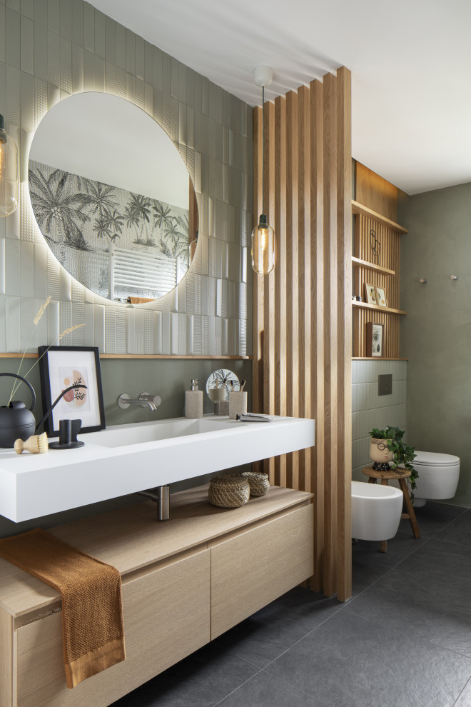 Пример оригинального дизайна: узкая и длинная ванная комната среднего размера в современном стиле с душем без бортиков, инсталляцией, зеленой плиткой, зелеными стенами, душевой кабиной, монолитной раковиной, белой столешницей, тумбой под одну раковину, подвесной тумбой и обоями на стенах