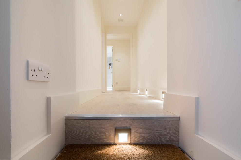 This is an example of a contemporary hallway in London with beige walls, medium hardwood floors and beige floor.