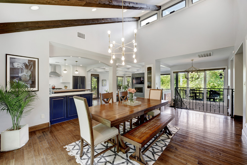 This is an example of a country open plan dining in Austin with white walls, dark hardwood floors and brown floor.
