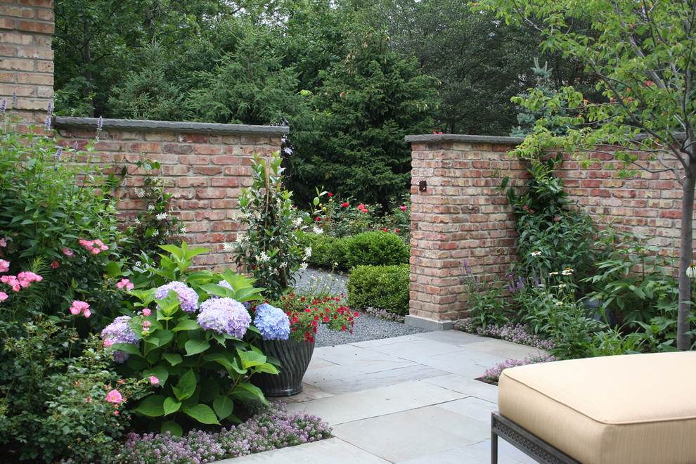 This is an example of a traditional garden in Chicago with natural stone pavers and with flowerbed.