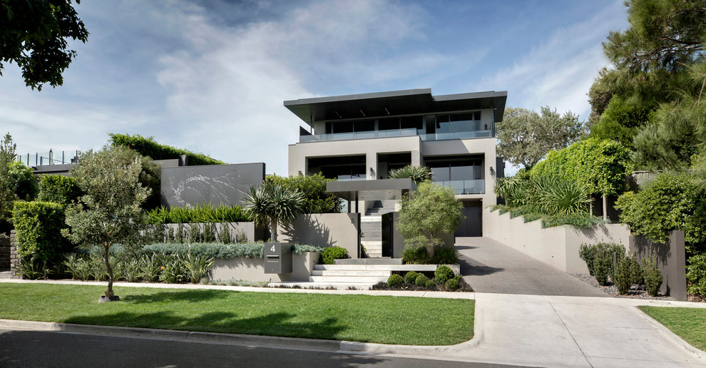 This is an example of a contemporary three-storey grey house exterior in Melbourne with a flat roof.