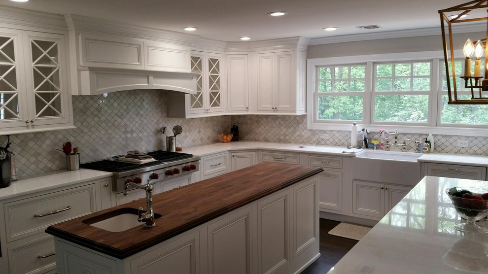 Example of a huge transitional l-shaped dark wood floor eat-in kitchen design in New York with a farmhouse sink, shaker cabinets, white cabinets, marble countertops, white backsplash, porcelain backsplash, stainless steel appliances and two islands