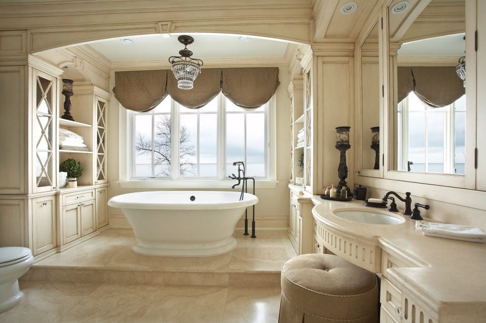 Inspiration for an expansive traditional master bathroom in Los Angeles with beige cabinets, a freestanding tub, a one-piece toilet, beige walls, porcelain floors, an undermount sink, engineered quartz benchtops, beige floor, beige benchtops, an enclosed toilet, a single vanity and wood walls.