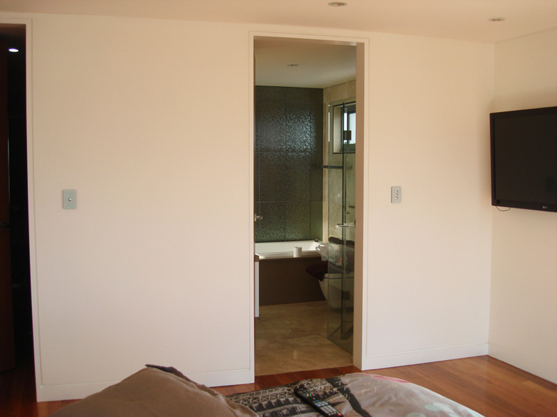 This is an example of a mid-sized modern master bedroom in Sydney with white walls, plywood floors and brown floor.