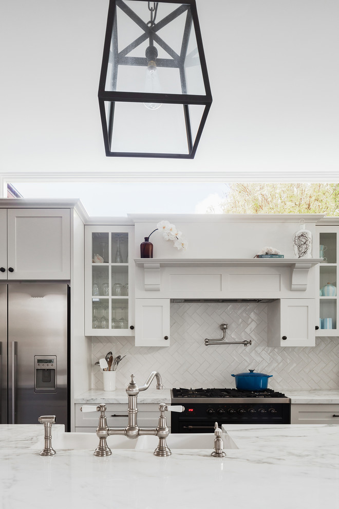 Photo of a large transitional u-shaped eat-in kitchen in Sydney with a double-bowl sink, raised-panel cabinets, white cabinets, marble benchtops, white splashback, ceramic splashback, stainless steel appliances, with island, dark hardwood floors and black floor.