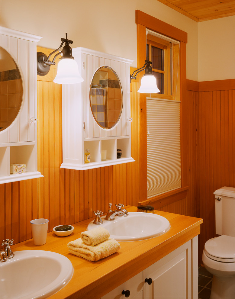 Photo of a mid-sized arts and crafts 3/4 bathroom in Portland Maine with a drop-in sink, raised-panel cabinets, white cabinets, wood benchtops, a two-piece toilet, beige walls and slate floors.