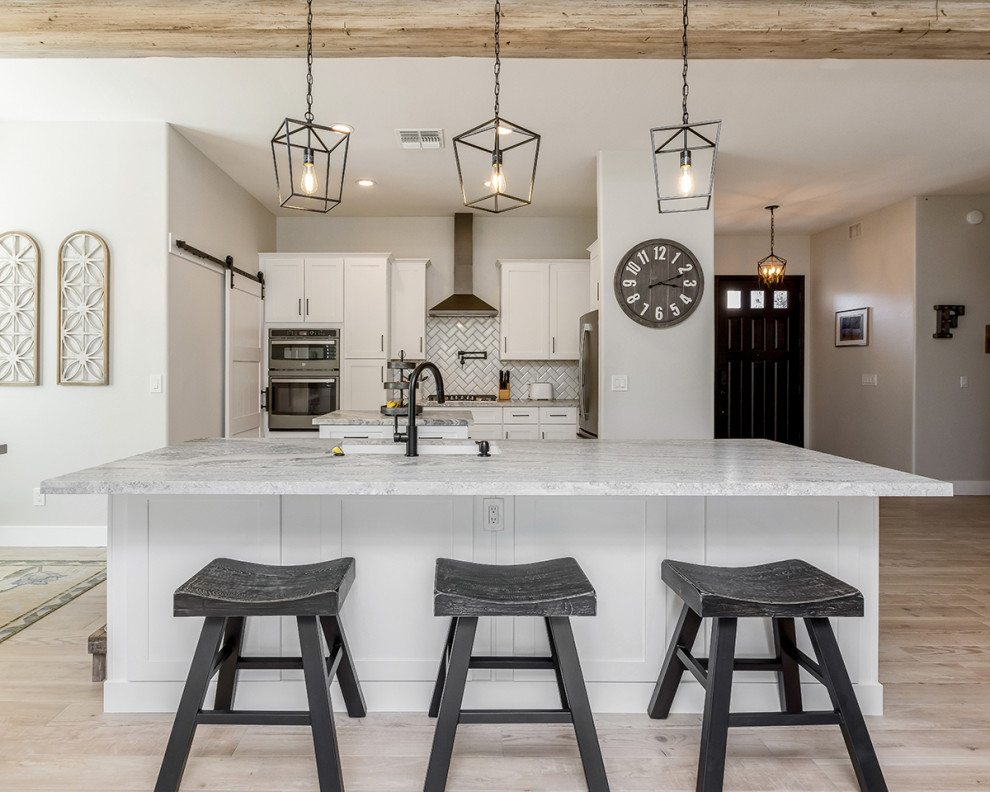 Inspiration for a mid-sized transitional single-wall eat-in kitchen in Phoenix with an undermount sink, shaker cabinets, white cabinets, granite benchtops, white splashback, ceramic splashback, stainless steel appliances, porcelain floors, multiple islands, brown floor and white benchtop.