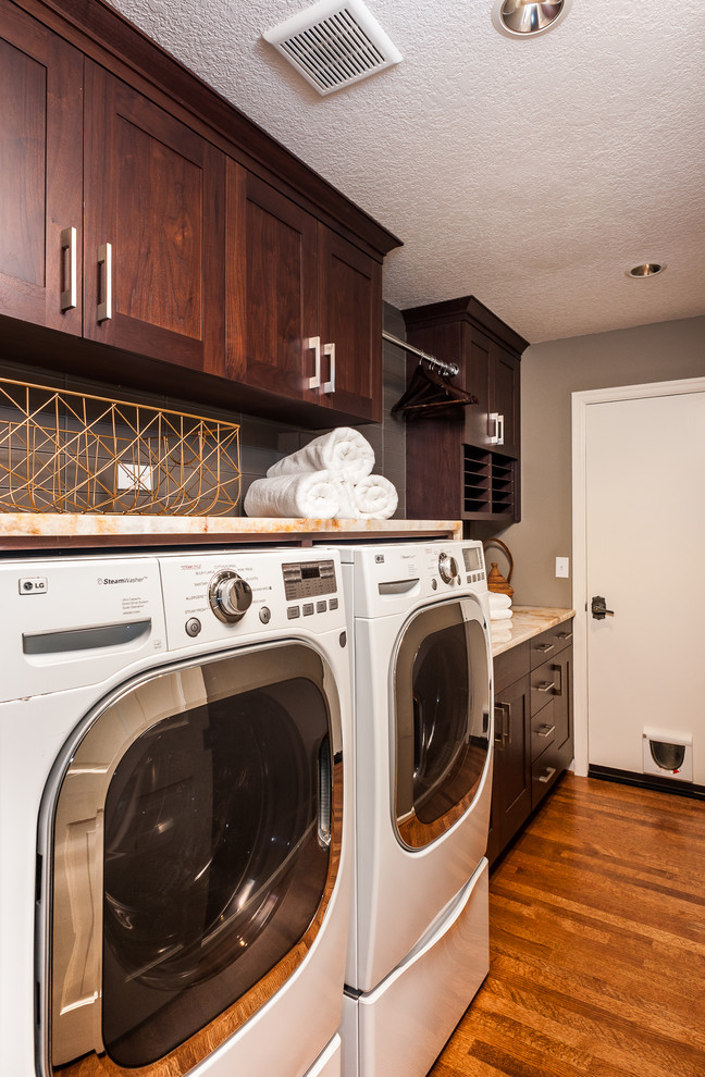 Design ideas for a large transitional laundry room in Portland with an undermount sink, recessed-panel cabinets, brown cabinets, granite benchtops, grey walls, medium hardwood floors, a side-by-side washer and dryer, brown floor and multi-coloured benchtop.