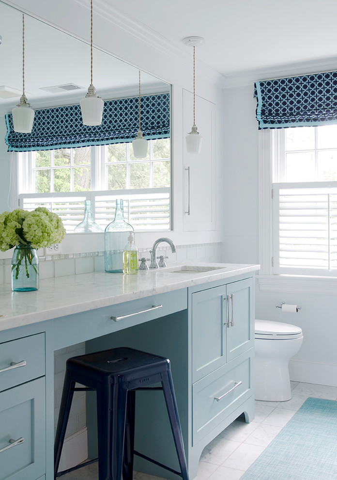 This is an example of a beach style bathroom in Boston with an undermount sink, shaker cabinets, blue cabinets, white tile and white walls.