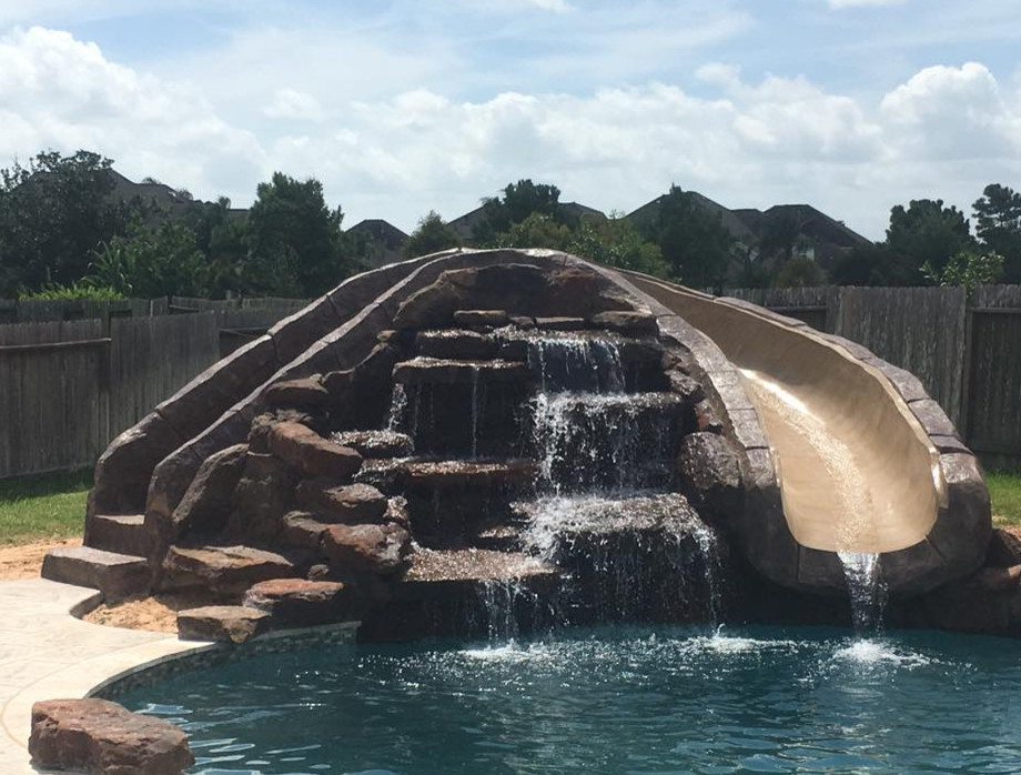 This is an example of a mid-sized country backyard custom-shaped natural pool in Orange County with a water slide and tile.