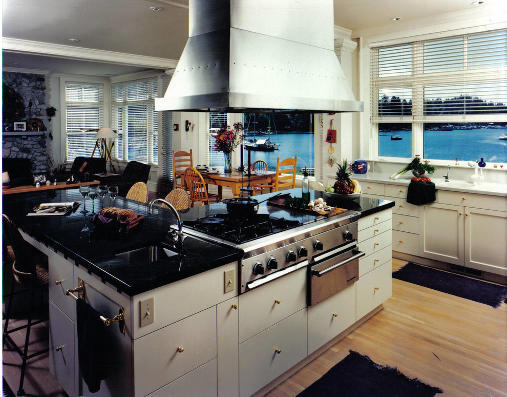 Mid-sized transitional l-shaped light wood floor eat-in kitchen photo with an undermount sink, flat-panel cabinets, white cabinets, granite countertops, stainless steel appliances and an island