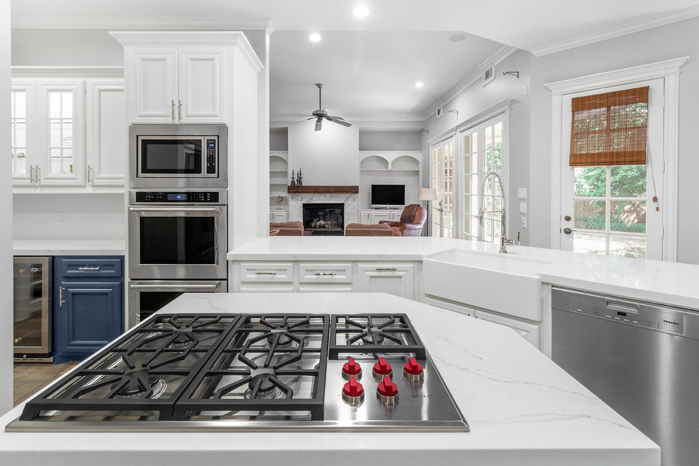 Inspiration for a mid-sized transitional u-shaped eat-in kitchen in Houston with a farmhouse sink, recessed-panel cabinets, white cabinets, quartz benchtops, white splashback, limestone splashback, stainless steel appliances, slate floors, with island, brown floor and white benchtop.