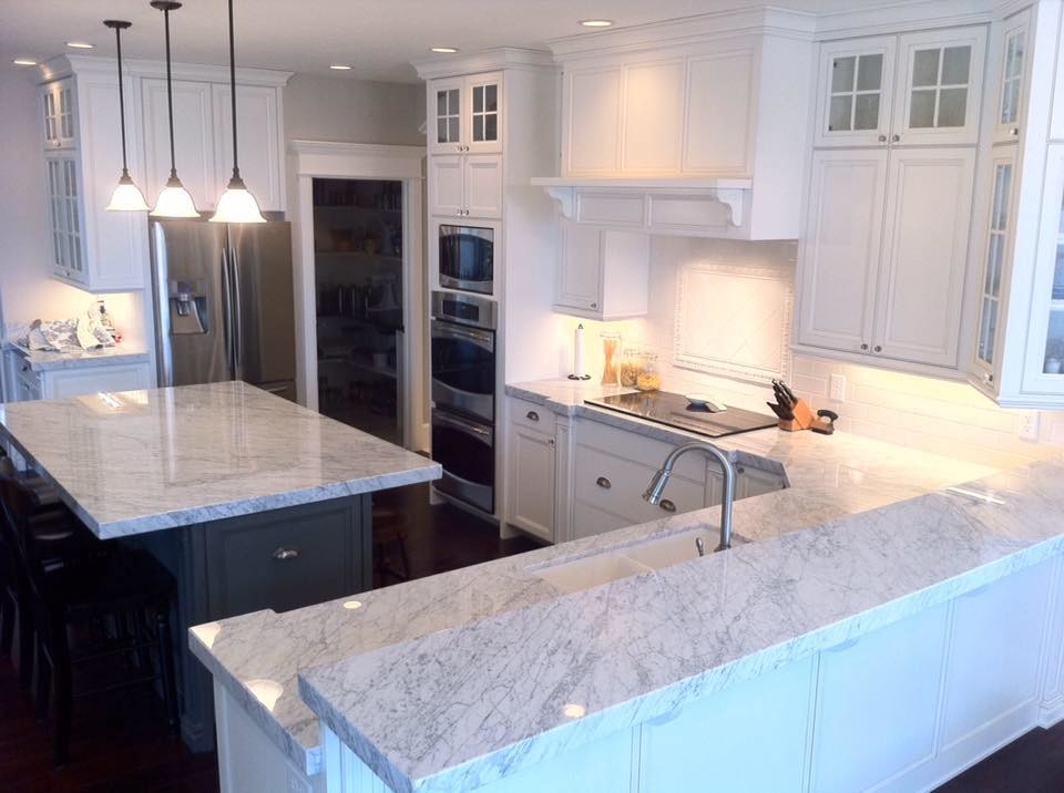 Mid-sized transitional u-shaped dark wood floor kitchen photo with a double-bowl sink, recessed-panel cabinets, white cabinets, marble countertops, white backsplash, porcelain backsplash, stainless steel appliances and an island