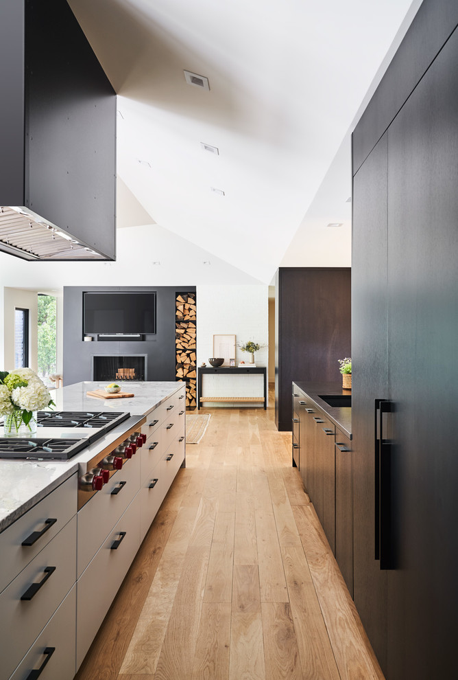 Design ideas for a contemporary galley kitchen in Kansas City with an undermount sink, flat-panel cabinets, black cabinets, light hardwood floors, brown floor and black benchtop.