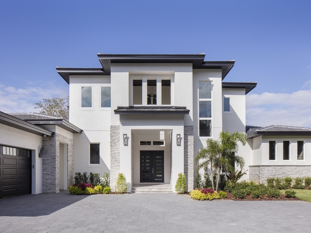 Photo of a large modern two-storey stucco white house exterior in Orlando with a gable roof and a tile roof.