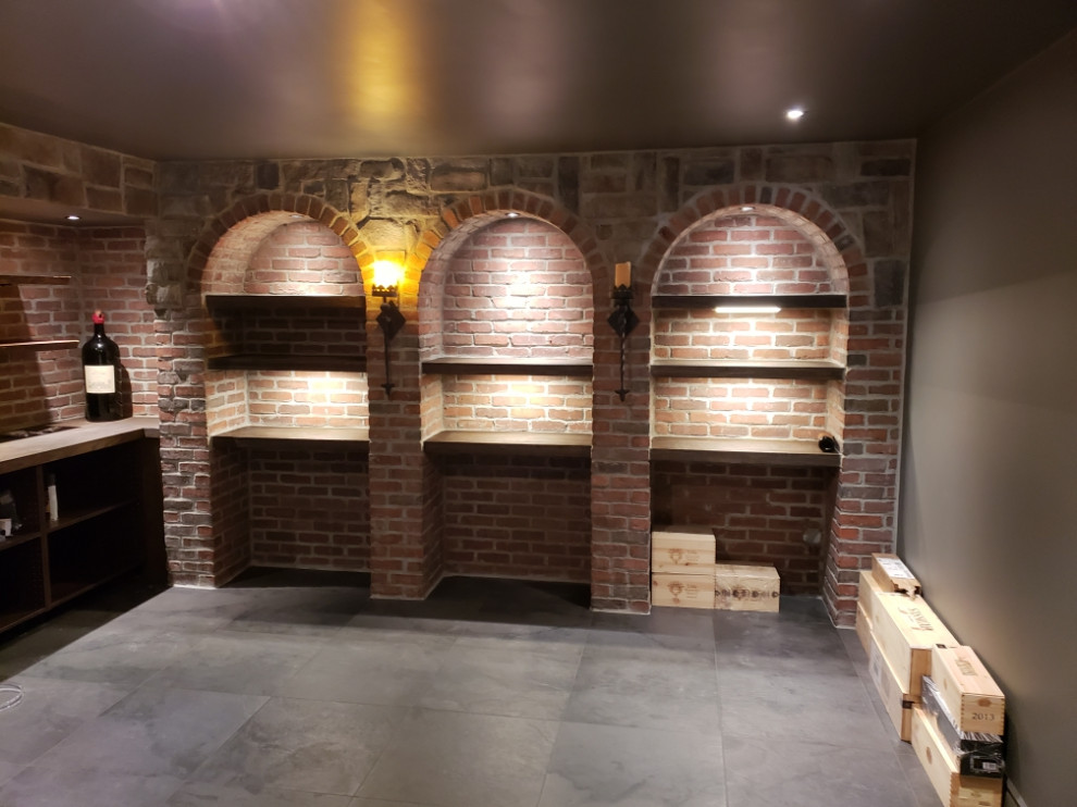 Large country wine cellar in Toronto with porcelain floors, display racks and grey floor.