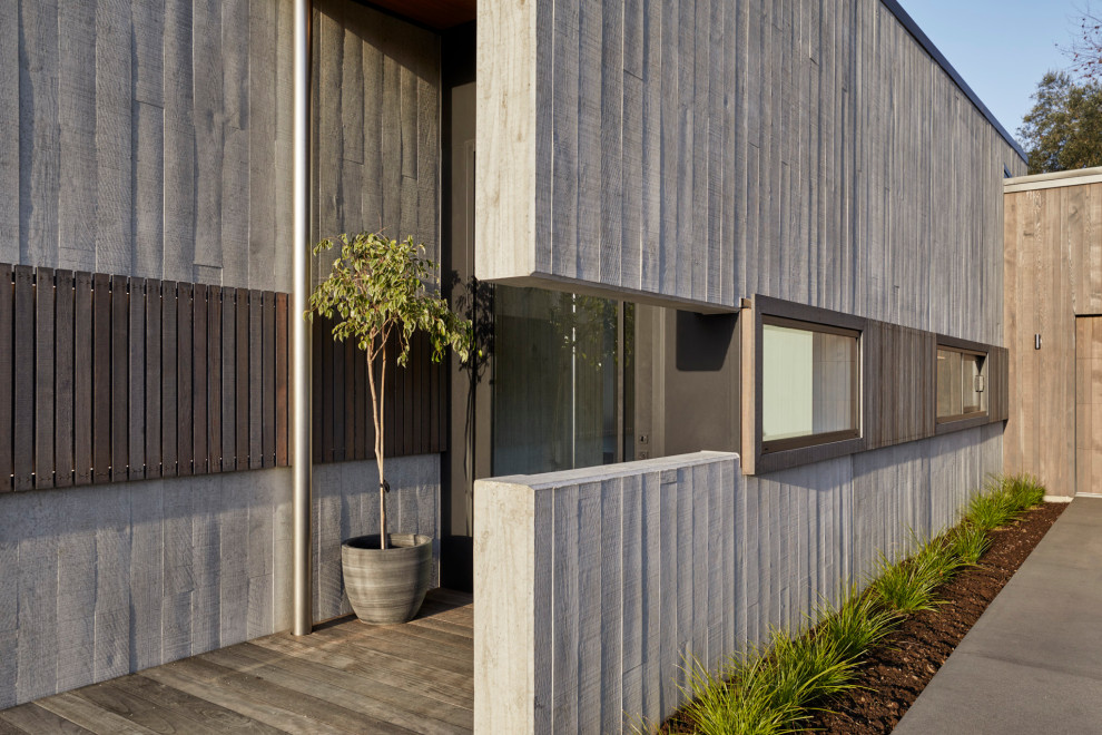 Diseño de fachada de casa gris contemporánea de una planta con revestimiento de hormigón