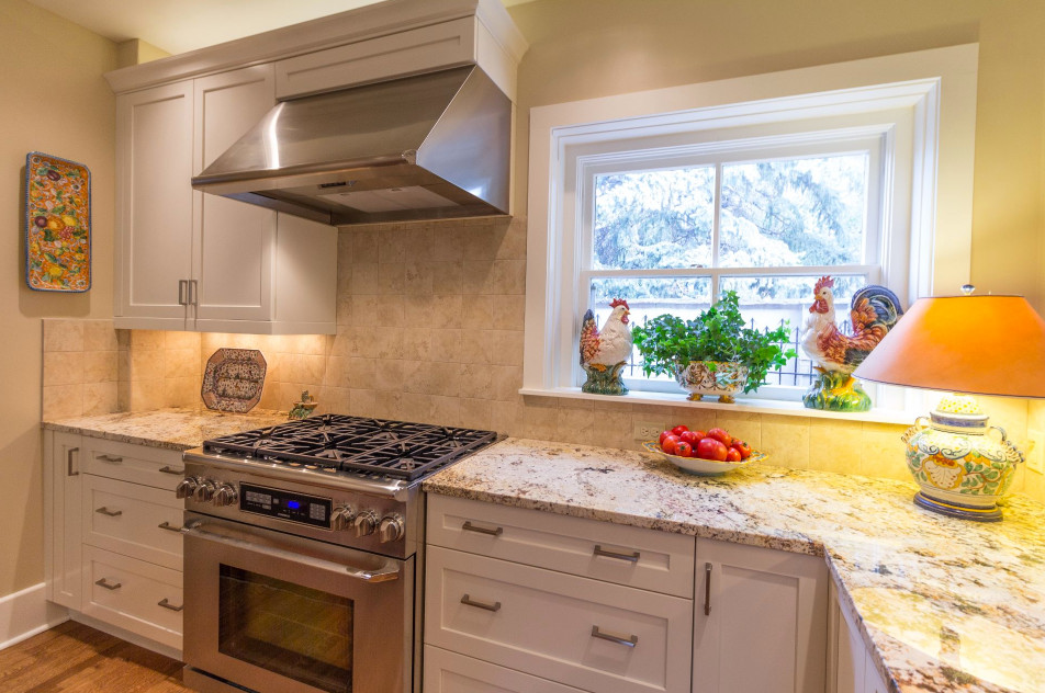 Large transitional u-shaped brown floor and medium tone wood floor enclosed kitchen photo in Denver with a double-bowl sink, shaker cabinets, white cabinets, granite countertops, beige backsplash, ceramic backsplash, stainless steel appliances and an island