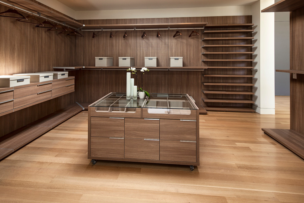 Photo of an expansive contemporary gender-neutral dressing room in Los Angeles with open cabinets, dark wood cabinets, light hardwood floors and brown floor.