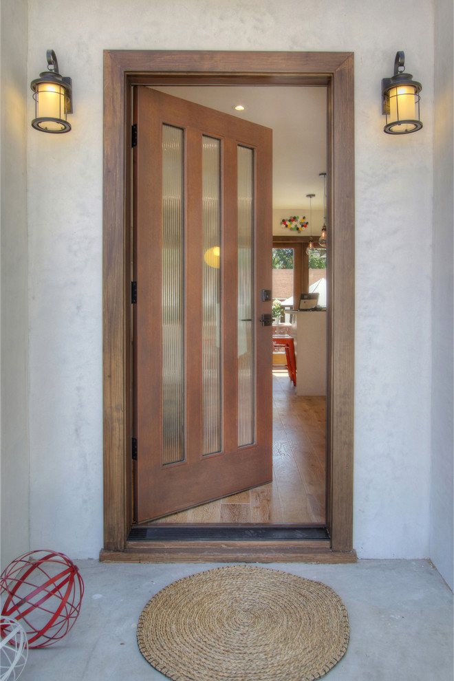 Small eclectic front door in Los Angeles with white walls, light hardwood floors, a single front door and a dark wood front door.