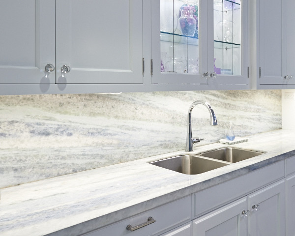Large transitional l-shaped medium tone wood floor open concept kitchen photo in Toronto with an undermount sink, shaker cabinets, white cabinets, quartz countertops, multicolored backsplash, stone slab backsplash, stainless steel appliances and an island
