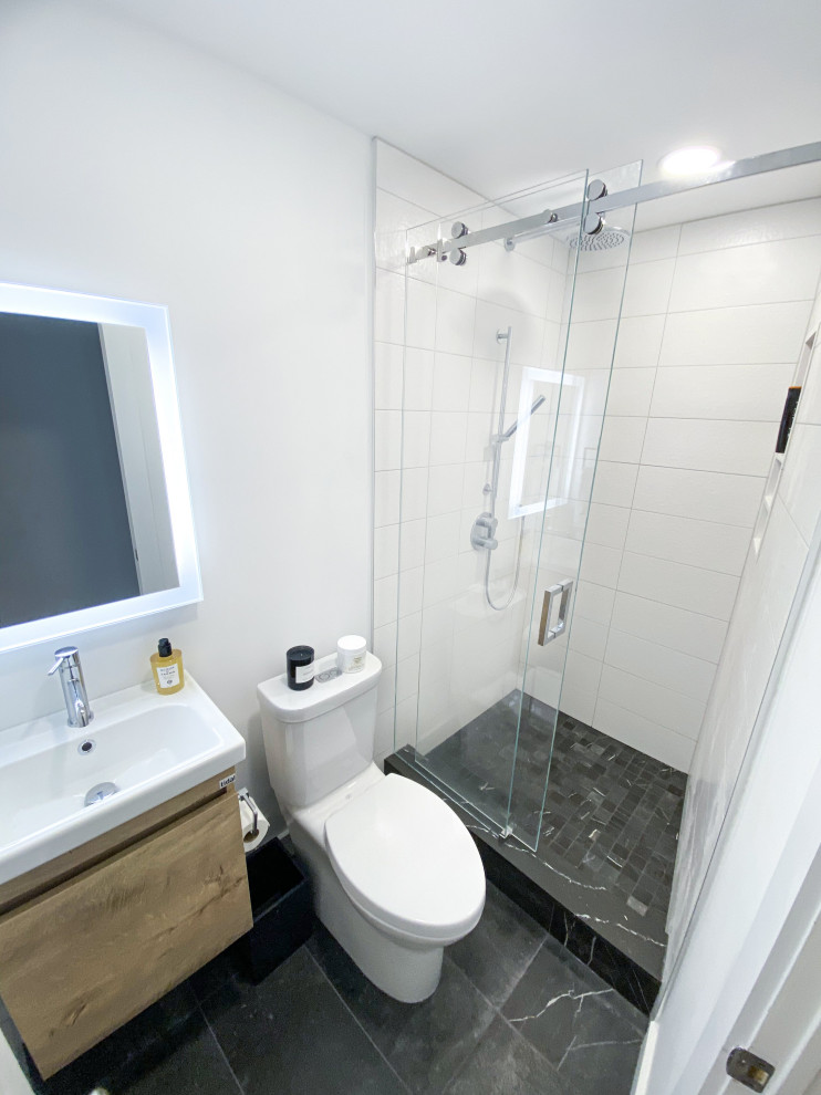 This is an example of a small modern shower room bathroom in Toronto with flat-panel cabinets, light wood cabinets, an alcove shower, a two-piece toilet, white tiles, ceramic tiles, white walls, porcelain flooring, an integrated sink, solid surface worktops, grey floors, a sliding door, white worktops, a wall niche, a single sink, a floating vanity unit and wallpapered walls.