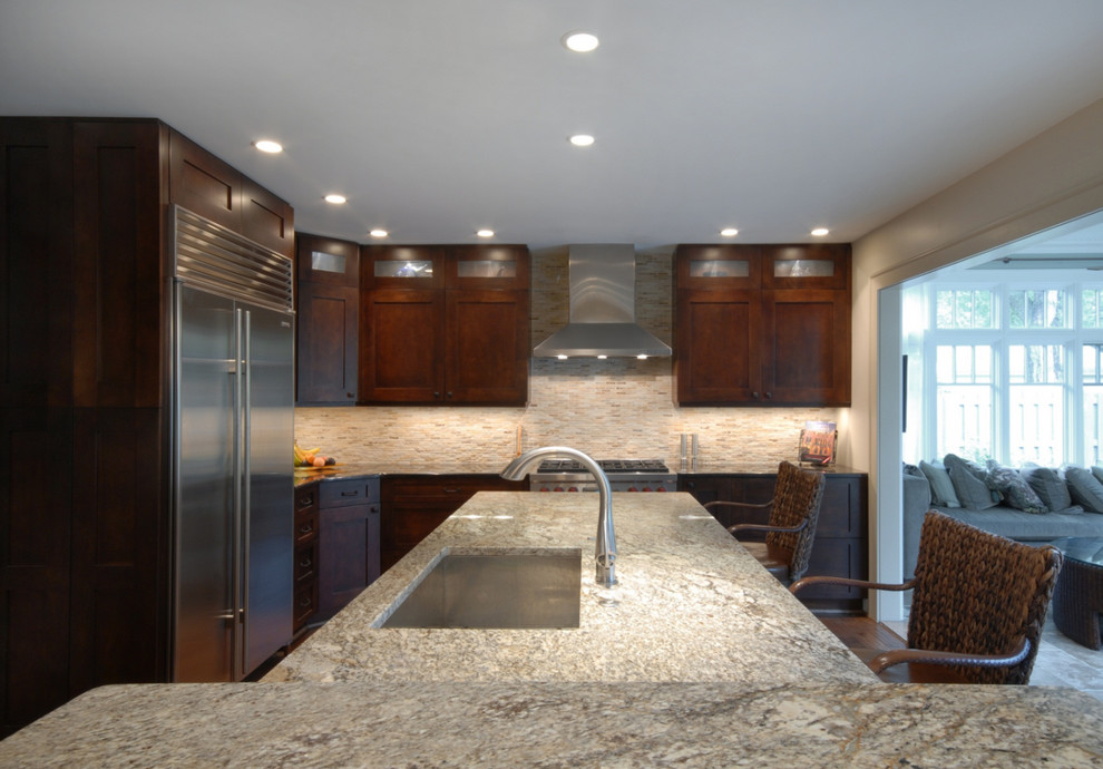 Large modern l-shaped eat-in kitchen in Detroit with an undermount sink, recessed-panel cabinets, medium wood cabinets, granite benchtops, brown splashback, stone tile splashback, stainless steel appliances, dark hardwood floors and with island.