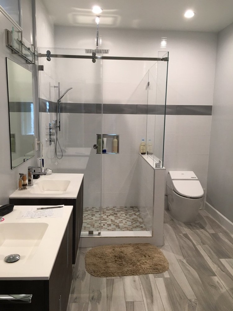Inspiration for a mid-sized contemporary master bathroom in San Francisco with flat-panel cabinets, dark wood cabinets, an alcove shower, a one-piece toilet, beige tile, mosaic tile, grey walls, light hardwood floors, an integrated sink and solid surface benchtops.