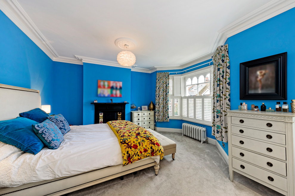 Transitional bedroom in London with blue walls, carpet and grey floor.