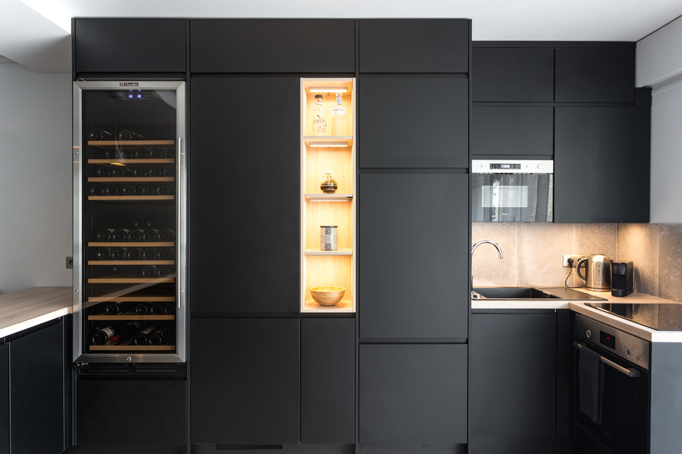 Design ideas for a scandinavian l-shaped kitchen in Paris with a single-bowl sink, flat-panel cabinets, black cabinets, grey splashback, panelled appliances, a peninsula and grey benchtop.