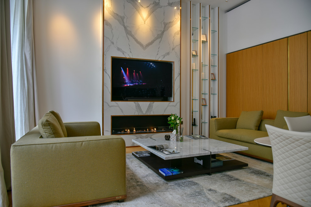 This is an example of a small contemporary open concept living room in London with white walls, light hardwood floors, a ribbon fireplace, a stone fireplace surround, a built-in media wall, beige floor and panelled walls.
