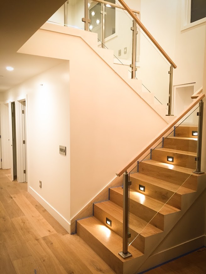 This is an example of a large modern wood u-shaped staircase in San Francisco with wood risers and glass railing.