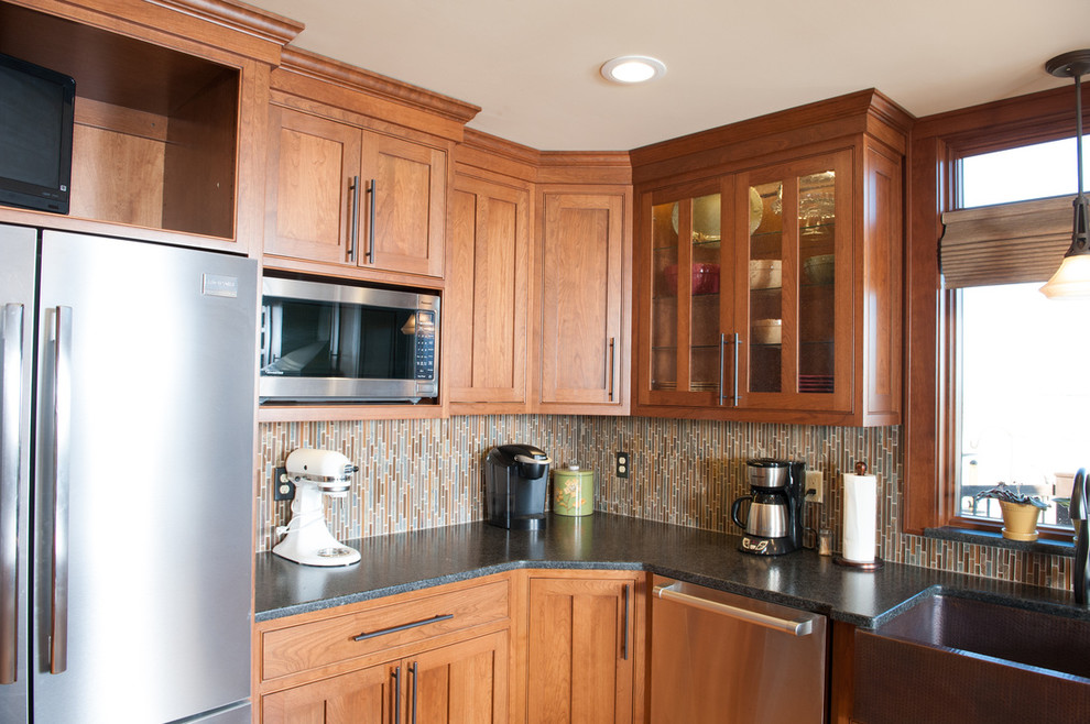 Mid-sized transitional l-shaped medium tone wood floor eat-in kitchen photo in Orange County with a farmhouse sink, shaker cabinets, medium tone wood cabinets, granite countertops, multicolored backsplash, matchstick tile backsplash, stainless steel appliances and an island