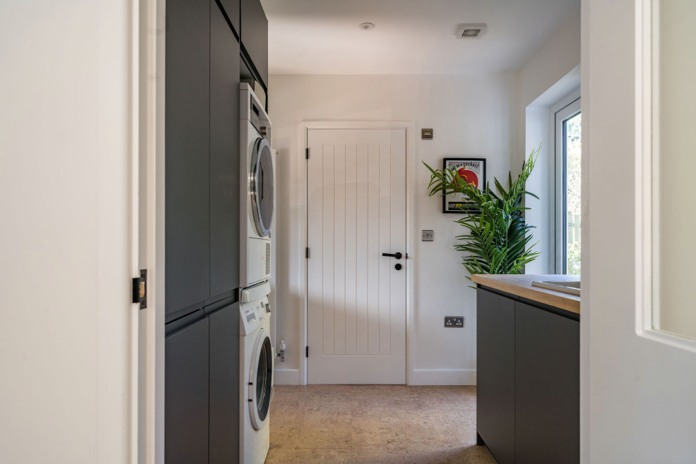 Mid-sized modern galley dedicated laundry room in Oxfordshire with an integrated sink, flat-panel cabinets, grey cabinets, wood benchtops, beige splashback, ceramic splashback, white walls, cork floors, beige floor and beige benchtop.