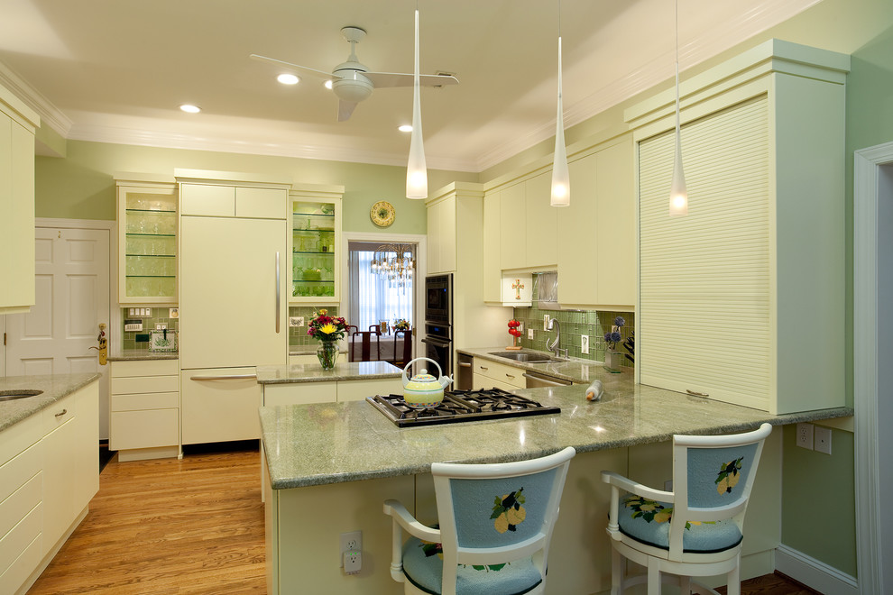 Design ideas for a large contemporary l-shaped eat-in kitchen in Raleigh with a double-bowl sink, flat-panel cabinets, yellow cabinets, granite benchtops, green splashback, glass tile splashback, panelled appliances, light hardwood floors and with island.