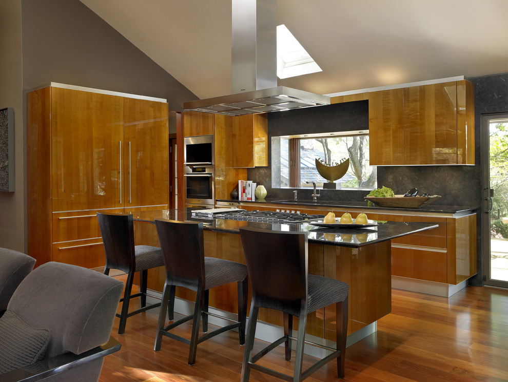 This is an example of a contemporary open plan kitchen in Chicago with flat-panel cabinets, medium wood cabinets and stainless steel appliances.