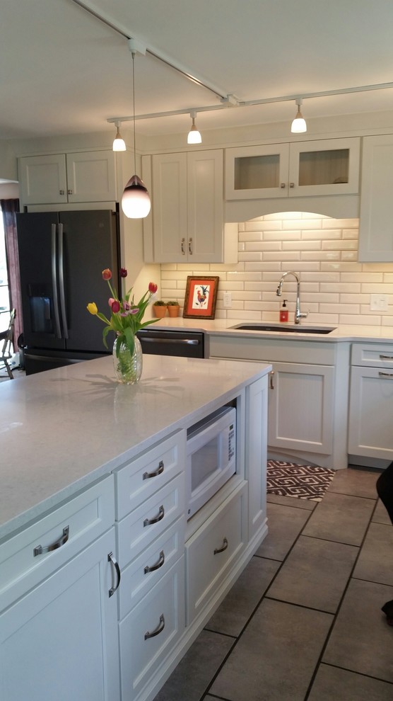 Photo of a mid-sized country l-shaped eat-in kitchen in Grand Rapids with an undermount sink, shaker cabinets, white cabinets, quartz benchtops, white splashback, subway tile splashback, coloured appliances, ceramic floors, with island, grey floor and white benchtop.
