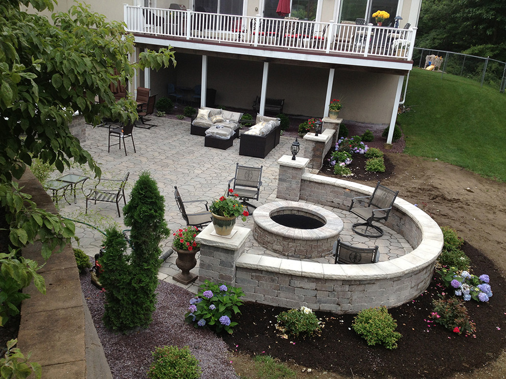 This is an example of a mid-sized traditional backyard patio in Boston with an outdoor kitchen, natural stone pavers and no cover.