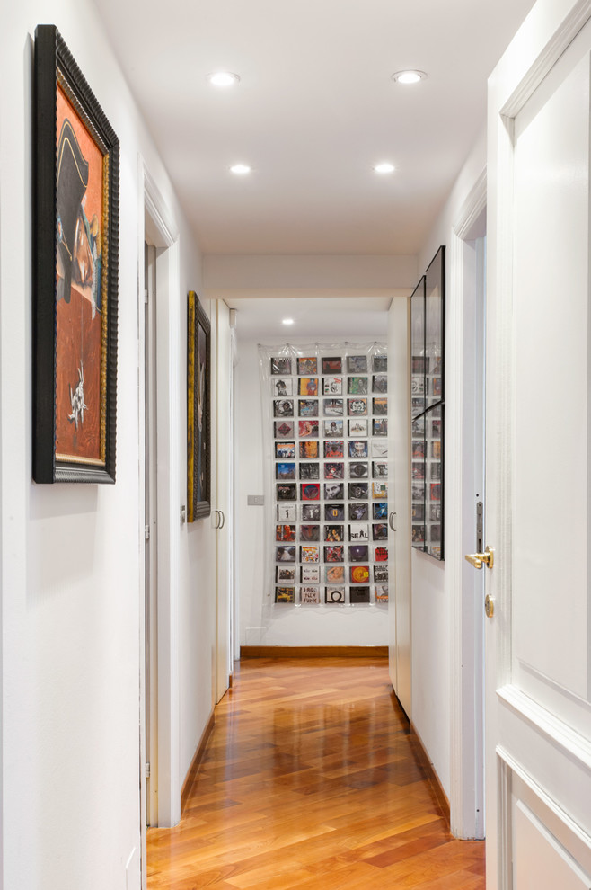 This is an example of an eclectic hallway in Turin with white walls, medium hardwood floors and brown floor.