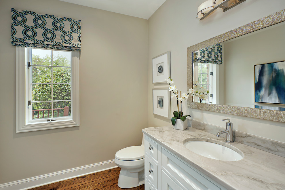 Mid-sized transitional powder room in Chicago with recessed-panel cabinets, white cabinets, a one-piece toilet, beige walls, medium hardwood floors, an undermount sink, granite benchtops and brown floor.