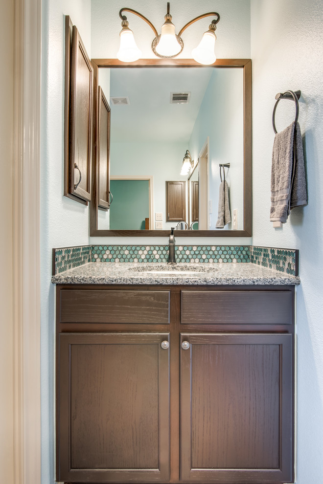 Mid-sized traditional master bathroom in Austin with shaker cabinets, brown cabinets, an alcove shower, blue tile, glass tile, blue walls, vinyl floors, an undermount sink, granite benchtops, grey floor, a hinged shower door and grey benchtops.
