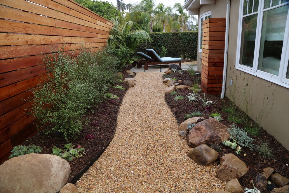 This is an example of a mid-sized tropical side yard partial sun garden in Santa Barbara with gravel.