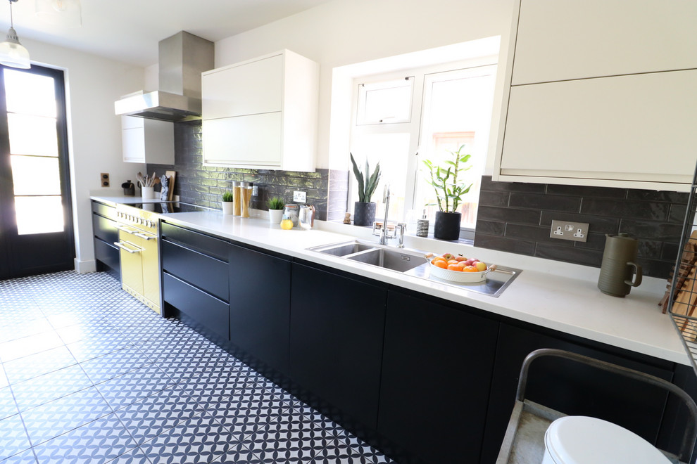 Photo of a large modern eat-in kitchen in Cambridgeshire with flat-panel cabinets, black cabinets, quartzite benchtops, grey splashback, ceramic splashback, ceramic floors, multi-coloured floor and white benchtop.