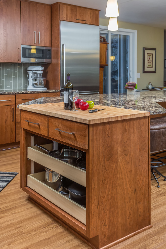 Example of a large l-shaped vinyl floor open concept kitchen design with an undermount sink, flat-panel cabinets, medium tone wood cabinets, quartz countertops, gray backsplash, glass tile backsplash, stainless steel appliances and an island
