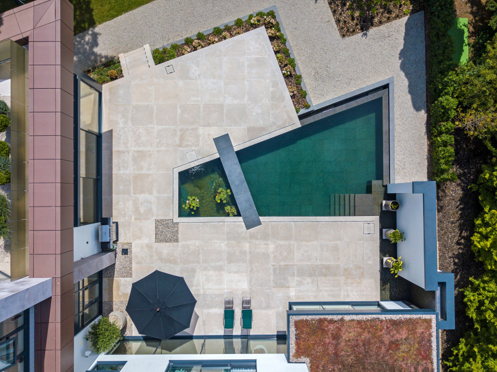 Ispirazione per una piscina a sfioro infinito minimalista personalizzata di medie dimensioni e dietro casa con paesaggistica bordo piscina e pavimentazioni in pietra naturale