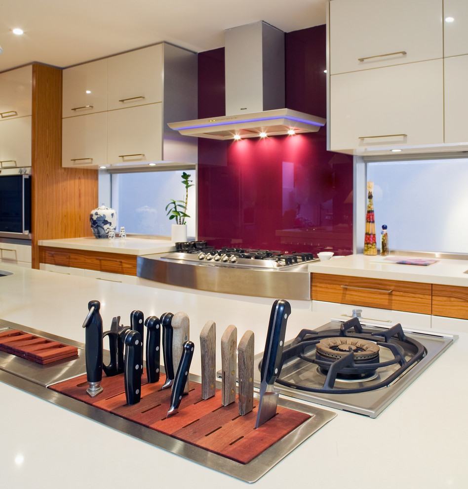 Design ideas for an asian open plan kitchen in Perth with an undermount sink, flat-panel cabinets, white cabinets, granite benchtops, white splashback, glass sheet splashback, stainless steel appliances, light hardwood floors and with island.