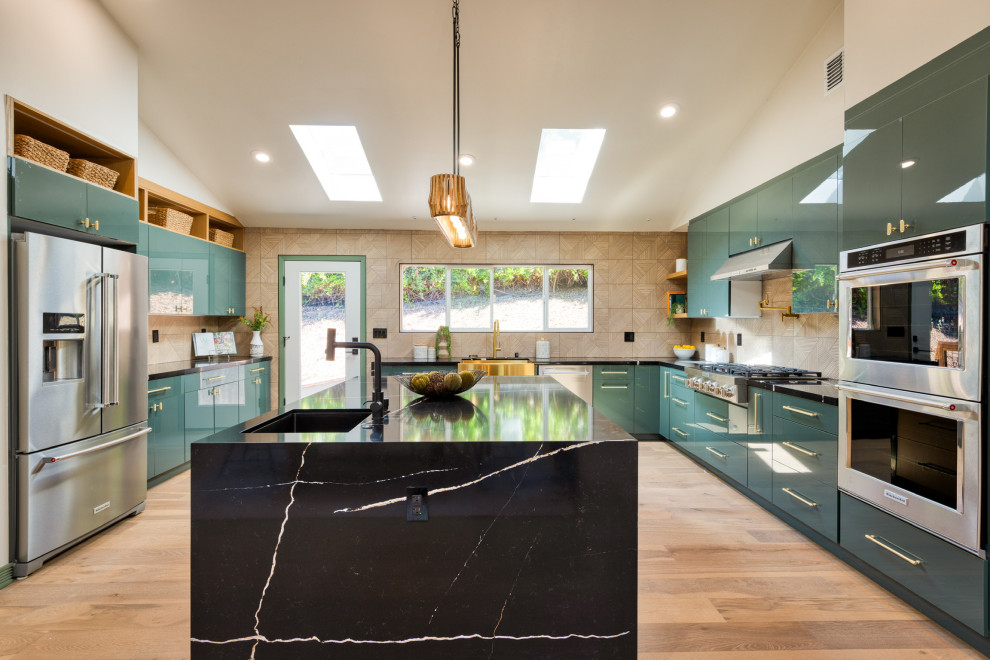 Eat-in kitchen - large contemporary light wood floor, brown floor and vaulted ceiling eat-in kitchen idea in San Francisco with a farmhouse sink, flat-panel cabinets, green cabinets, quartz countertops, brown backsplash, porcelain backsplash, stainless steel appliances, an island and black countertops