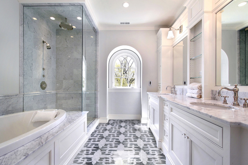 Inspiration for a large traditional master bathroom in New York with recessed-panel cabinets, white cabinets, a drop-in tub, a corner shower, gray tile, marble, grey walls, marble floors, an undermount sink, marble benchtops, multi-coloured floor and a hinged shower door.